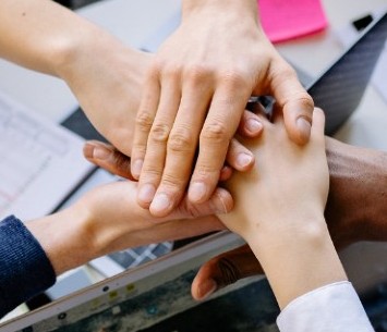 Diverse team joining hands, representing VHC Holdings partnerships across borders